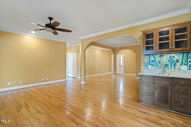 interior space featuring dark brown cabinetry, ceiling fan, sink, crown molding, and light wood-type flooring