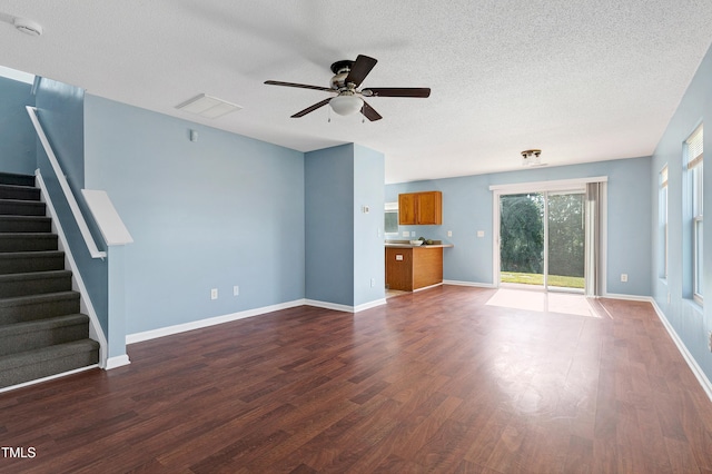 unfurnished living room featuring ceiling fan, dark hardwood / wood-style flooring, and a textured ceiling