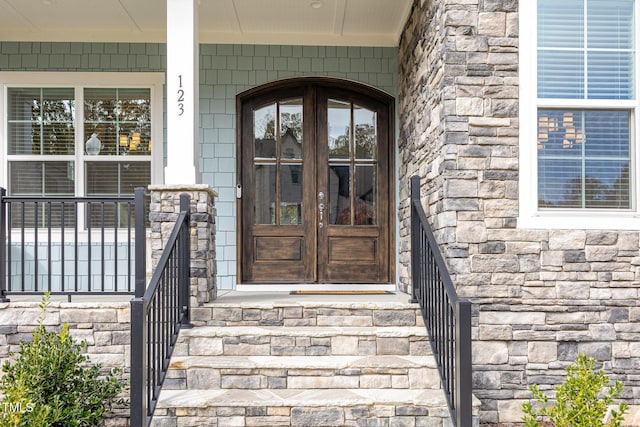 view of exterior entry featuring french doors and covered porch