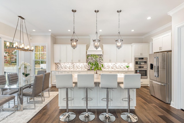 kitchen featuring a kitchen breakfast bar, an island with sink, pendant lighting, and appliances with stainless steel finishes