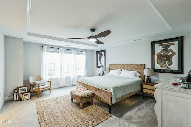 bedroom featuring carpet, a tray ceiling, ceiling fan, and baseboards