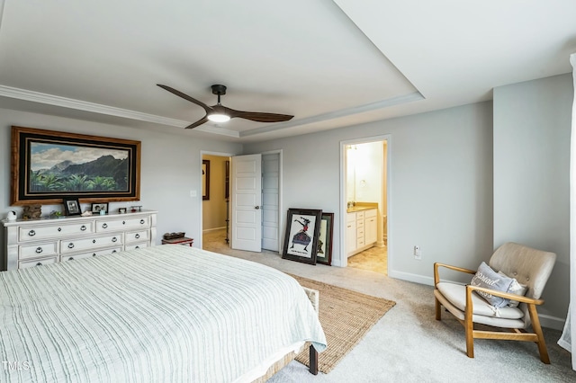 carpeted bedroom featuring a tray ceiling, ensuite bathroom, and ceiling fan