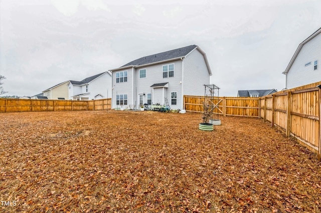 rear view of house featuring a fenced backyard