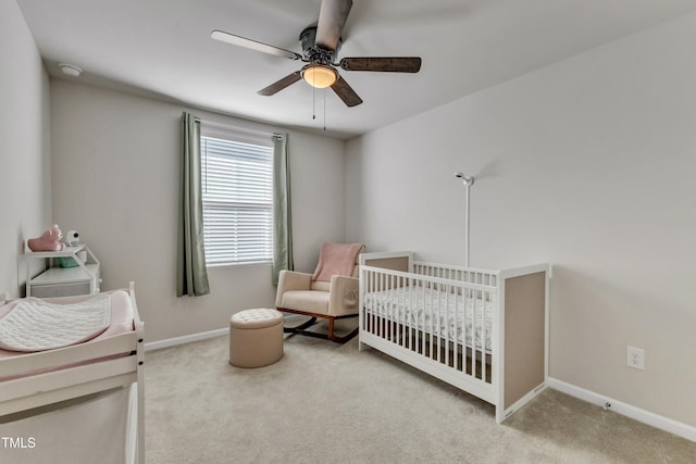 carpeted bedroom with ceiling fan and a nursery area