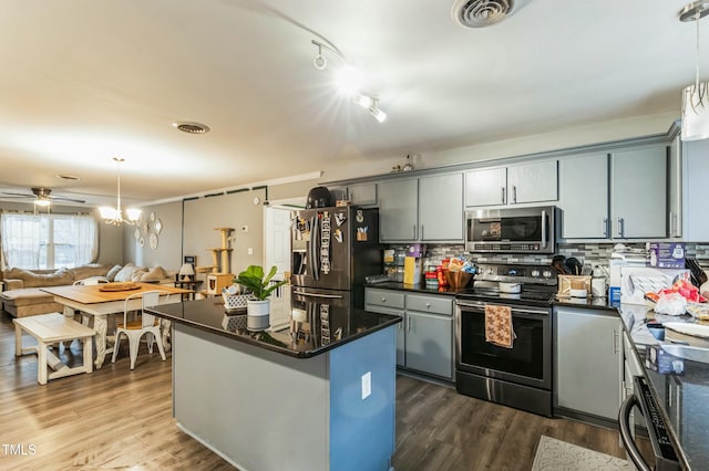 kitchen featuring pendant lighting, ceiling fan, appliances with stainless steel finishes, tasteful backsplash, and dark hardwood / wood-style flooring