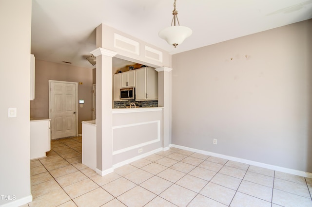 kitchen featuring ornate columns, tasteful backsplash, hanging light fixtures, light tile patterned floors, and white cabinets