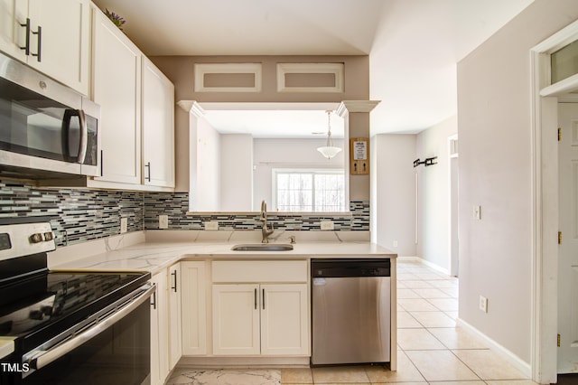 kitchen featuring appliances with stainless steel finishes, decorative light fixtures, sink, backsplash, and kitchen peninsula