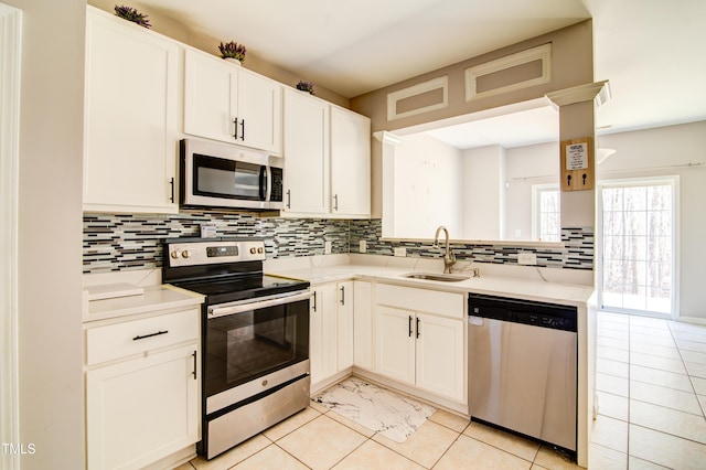 kitchen with appliances with stainless steel finishes, kitchen peninsula, sink, and white cabinets