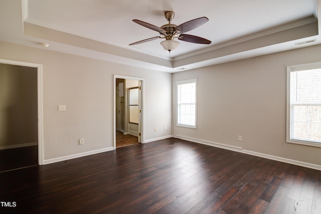 empty room featuring dark wood-type flooring, ceiling fan, ornamental molding, and a tray ceiling