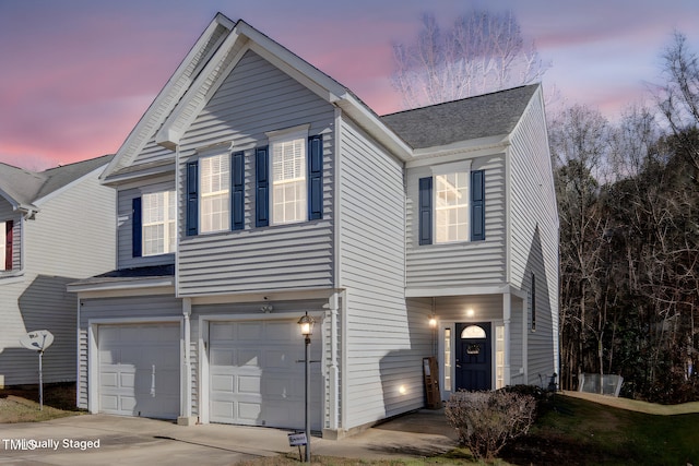 traditional-style home featuring an attached garage, driveway, and a shingled roof