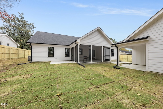 back of property with a yard, a patio area, and a sunroom