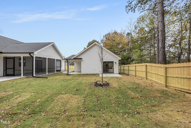 rear view of house featuring a yard, a patio area, and a sunroom