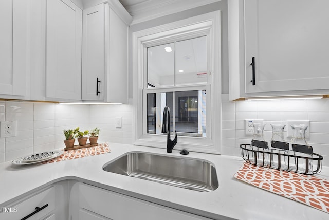 kitchen featuring backsplash, white cabinetry, and sink