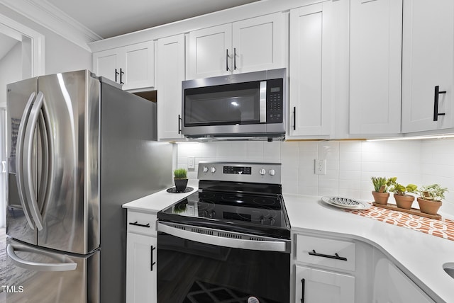 kitchen featuring white cabinets, appliances with stainless steel finishes, tasteful backsplash, and ornamental molding