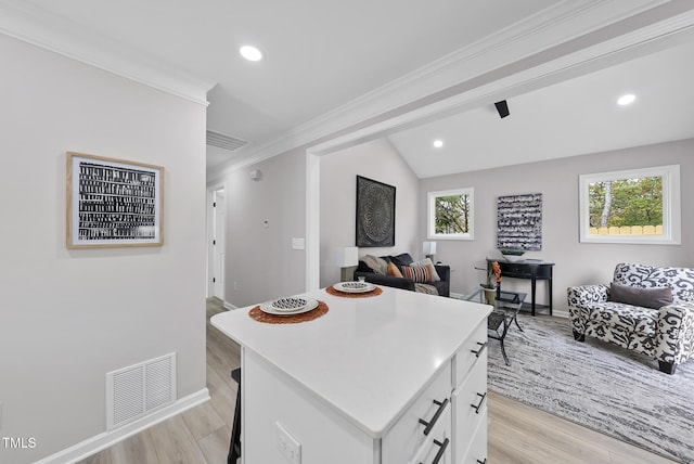 kitchen with white cabinets, a kitchen island, a wealth of natural light, and light hardwood / wood-style flooring