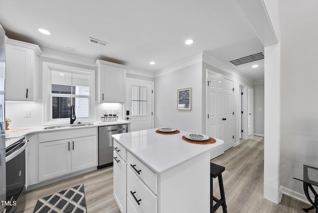 kitchen featuring stainless steel dishwasher, a kitchen island, sink, range, and white cabinetry