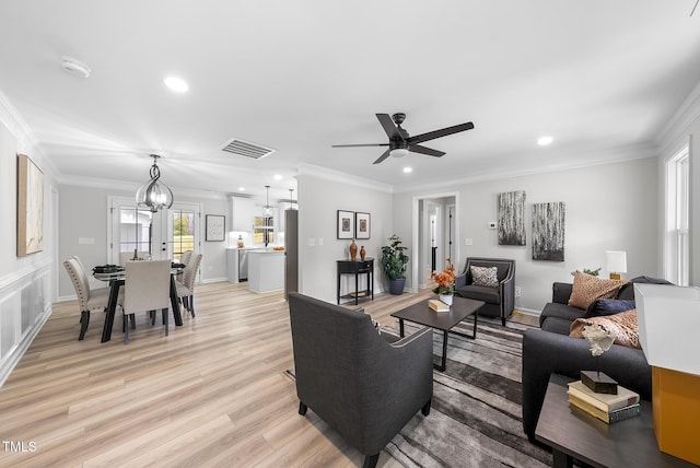 living room with crown molding, plenty of natural light, and light hardwood / wood-style flooring