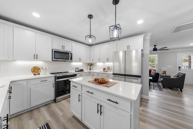 kitchen with white cabinetry, ceiling fan, a center island, stainless steel appliances, and tasteful backsplash