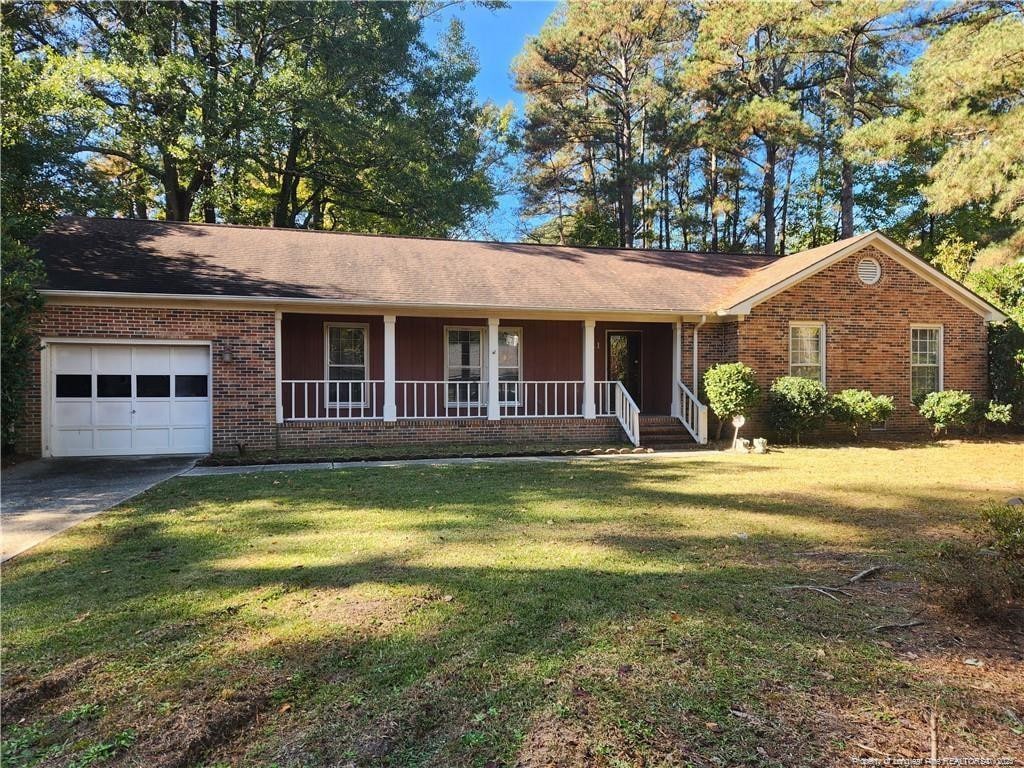 ranch-style home with a garage, brick siding, a front lawn, and a porch