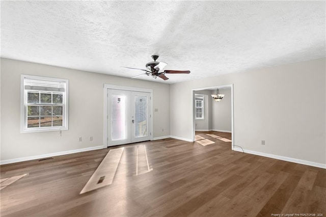 interior space featuring a textured ceiling, ceiling fan with notable chandelier, and dark hardwood / wood-style floors