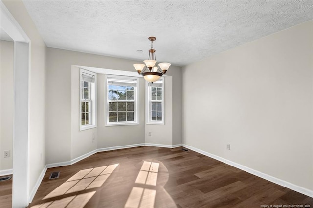 unfurnished dining area with a textured ceiling, dark hardwood / wood-style floors, and a notable chandelier