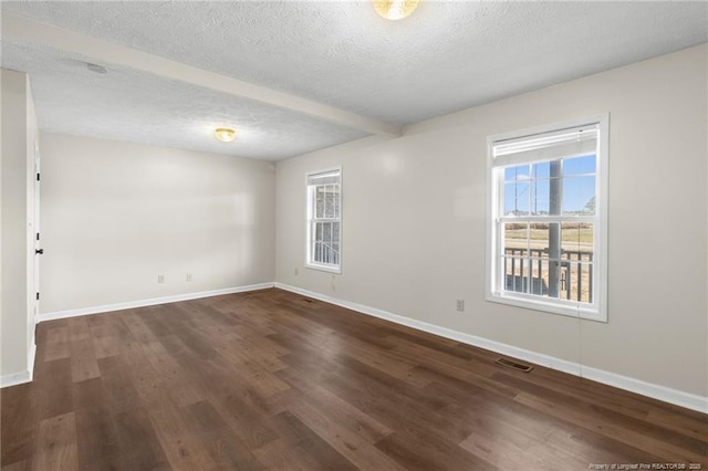 empty room featuring a textured ceiling and dark hardwood / wood-style flooring