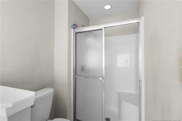 bathroom with a shower with shower door, a textured ceiling, and toilet