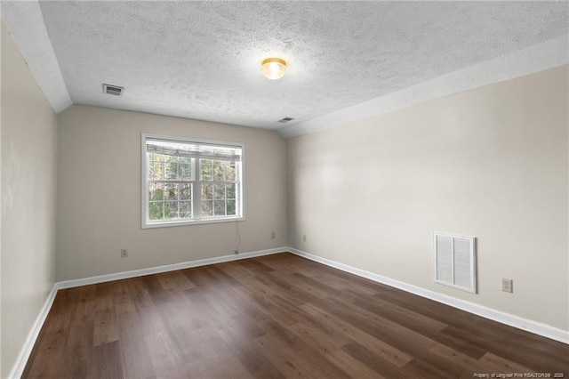 spare room featuring a textured ceiling, vaulted ceiling, and dark wood-type flooring