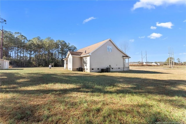 view of side of property featuring a lawn and central AC