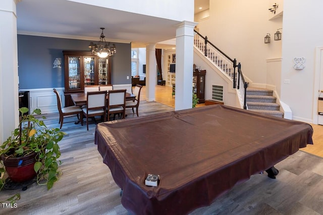 recreation room featuring decorative columns, crown molding, a notable chandelier, hardwood / wood-style floors, and pool table