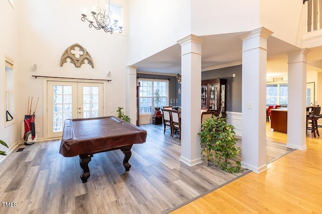 playroom with french doors, an inviting chandelier, ornamental molding, and wood-type flooring