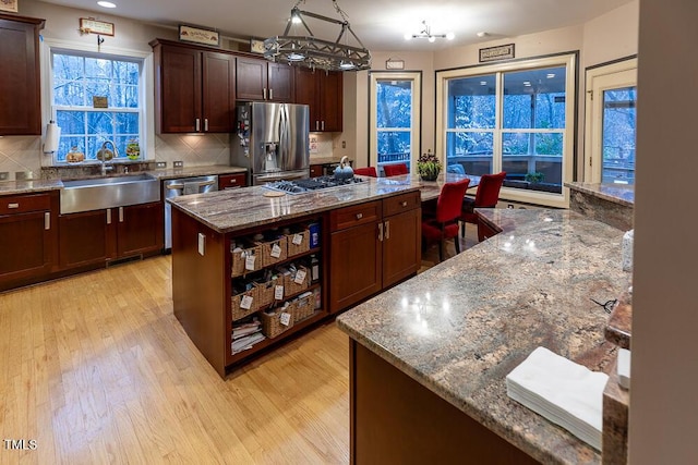 kitchen with backsplash, stone counters, a kitchen island, and appliances with stainless steel finishes