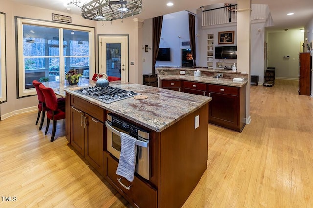 kitchen with light stone countertops, a center island, light hardwood / wood-style floors, and stainless steel gas stovetop