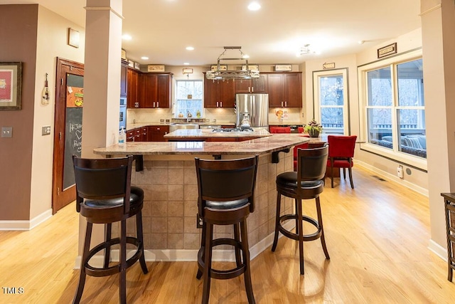 kitchen with a breakfast bar, light hardwood / wood-style floors, and stainless steel appliances