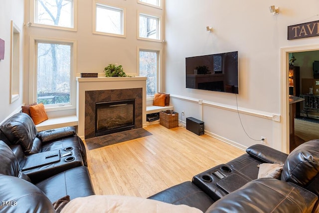 living room featuring wood-type flooring, a fireplace, and a towering ceiling