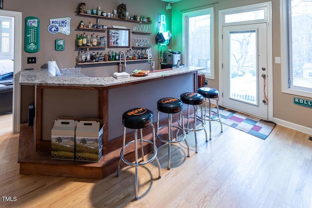 bar featuring light stone counters and light hardwood / wood-style flooring