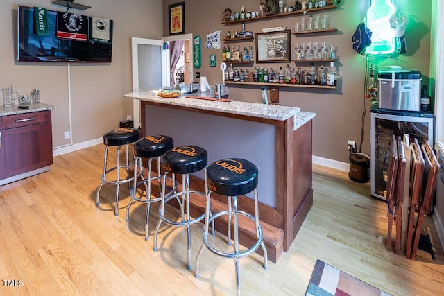 bar featuring light wood-type flooring and light stone counters