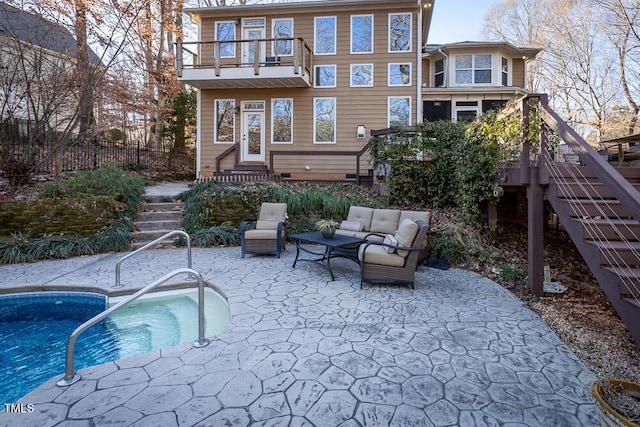 rear view of property featuring an outdoor living space, a patio area, a balcony, and a hot tub