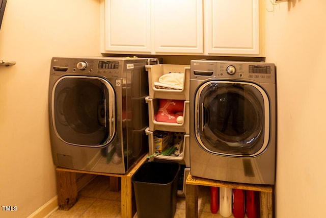 clothes washing area featuring cabinets, light tile patterned floors, and washing machine and dryer