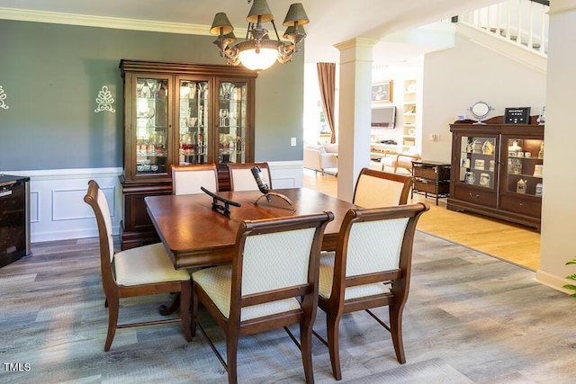 5240 Indigo Moon Way, Raleigh, NC 27613 - dining area with wood finished floors, a chandelier, a wainscoted wall, stairway, and decorative columns