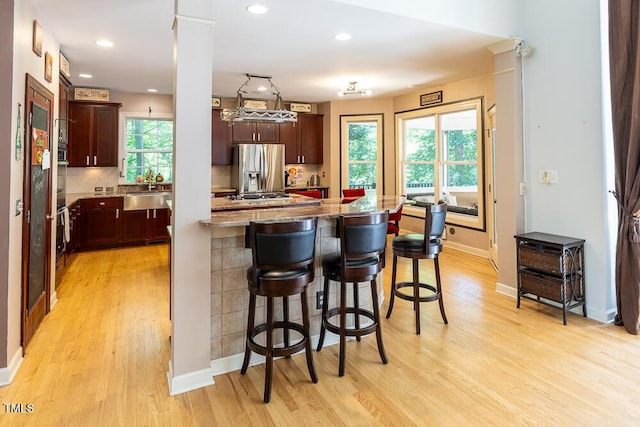 5240 Indigo Moon Way, Raleigh, NC 27613 - kitchen with stainless steel refrigerator with ice dispenser, light wood-style flooring, a breakfast bar area, gas cooktop, and light stone countertops