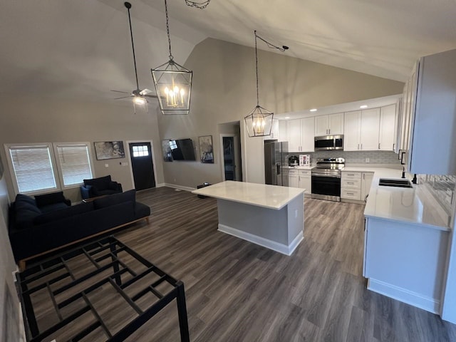 kitchen with backsplash, white cabinets, ceiling fan, appliances with stainless steel finishes, and decorative light fixtures