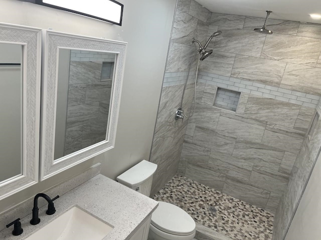 bathroom with vanity, toilet, and tiled shower