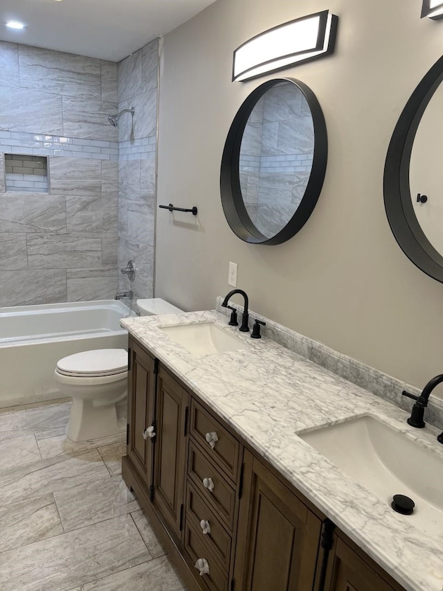 full bathroom with vanity, tiled shower / bath, and toilet