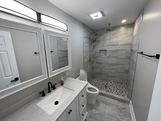 bathroom featuring vanity, toilet, and tiled shower