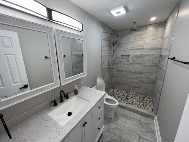 bathroom with vanity, toilet, and tiled shower