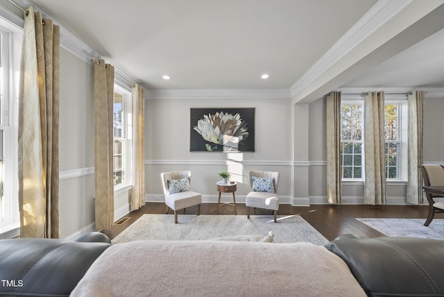 living area featuring dark hardwood / wood-style floors, crown molding, and plenty of natural light