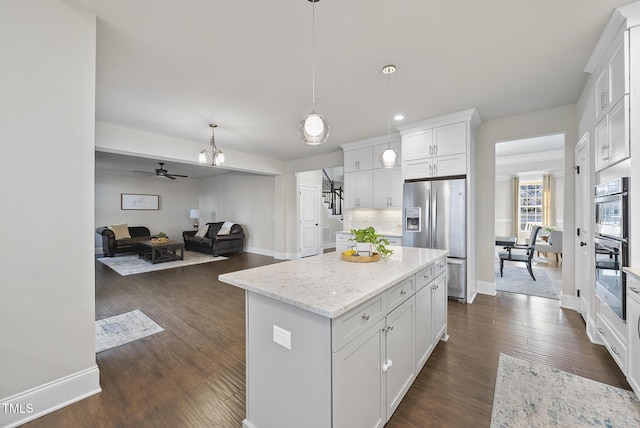 kitchen featuring stainless steel appliances, decorative light fixtures, a center island, white cabinetry, and ceiling fan