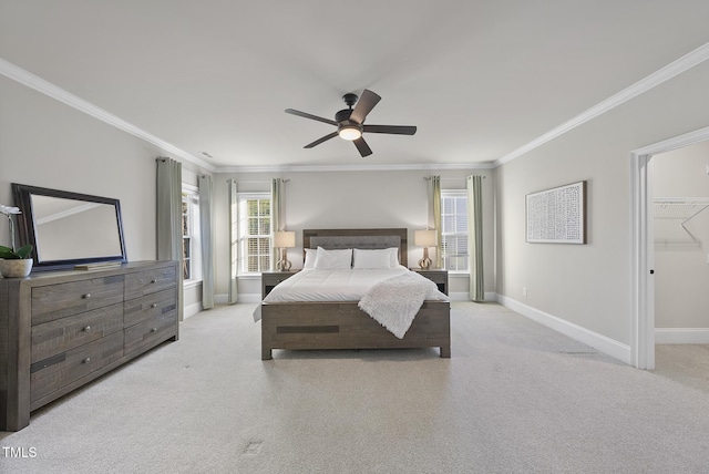 bedroom with ornamental molding, a closet, a walk in closet, ceiling fan, and light carpet