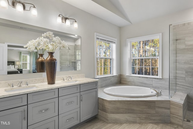 bathroom with tiled tub, vaulted ceiling, and vanity